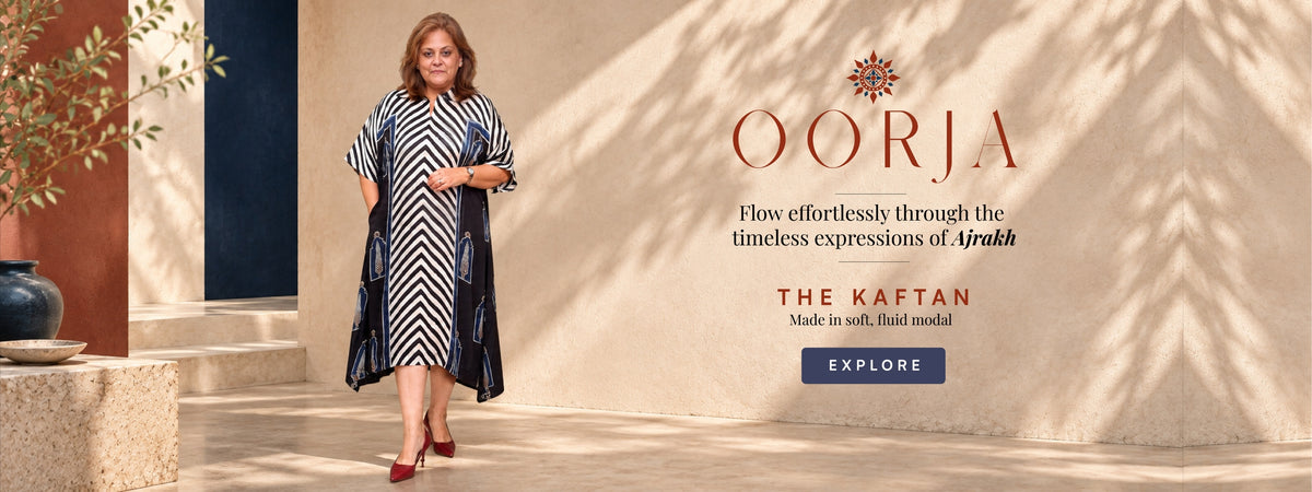 A woman models a black and white chevron patterned kaftan dress in a sunlit architectural setting. The ad features the brand name 'OORJA' and text promoting 'THE KAFTAN' on the right side.