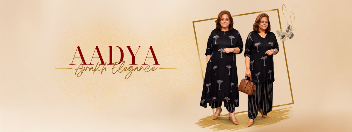 Two women modeling matching Aadya South Elegance loungewear sets against a warm beige background with elegant gold and red text. The set features a navy blue base with a white palm tree pattern, paired with white pants.